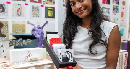 A female student holding up their work at a creative festival