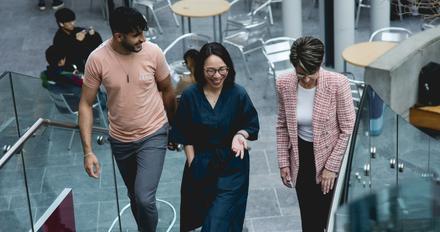 Three members of staff walking up some stairs
