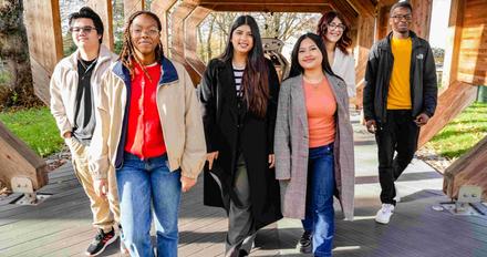Six students walking together under a wooden structure