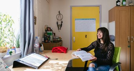 A woman sitting at a desk in a room with a yellow door at Usher Halls.
