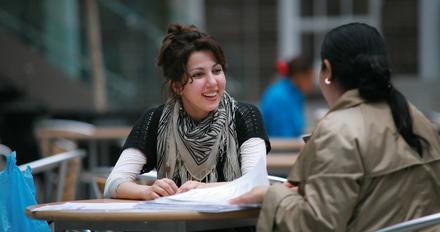 Two women sitting at a table, engaged in conversation and enjoying each other's company.