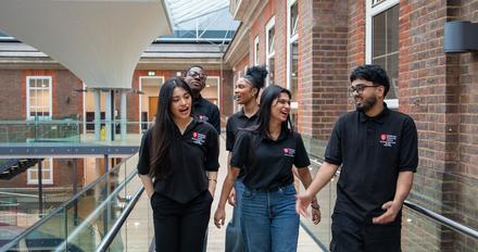 A group of young people walking along a corridor in an airy building