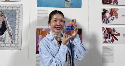 �������� University graduate Lotte Siu holds her award in front of a display of illustration