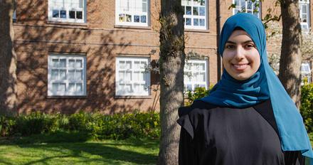Duha stood on campus on a sunny day with campus building in background
