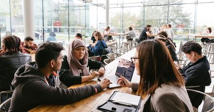Students studying around a table in bright busy room
