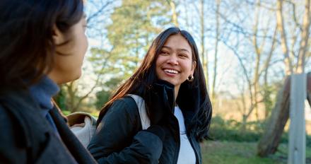 A smiling student walking through campus with a friend