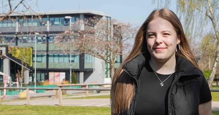Abbi on campus on a sunny day with building in background