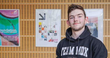 Toney - clearing student stood in front of gallery of work