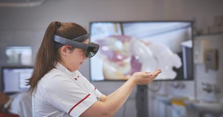 Student using VR with screen in background.
