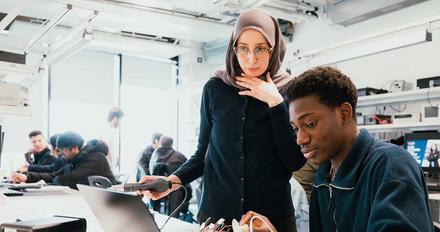 Two students looking at laptop on a desk