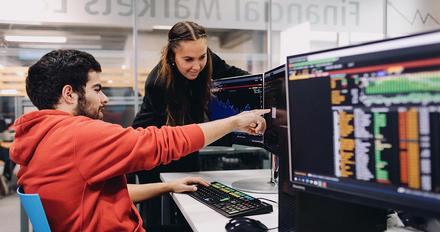 Two students sat at desk with computer
