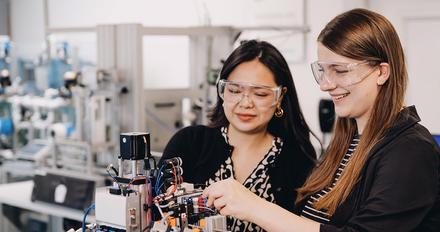 Two student using engineering equipment in lab
