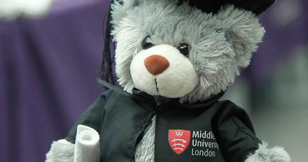 A teddy bear wearing a graduation cap and gown.