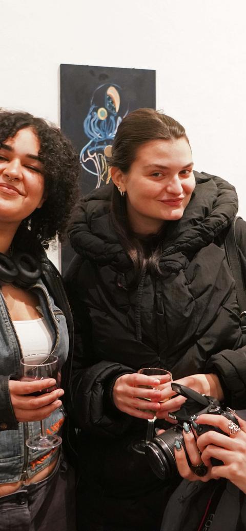 Three students smiling at the camera at an art show