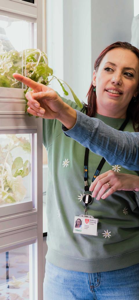 Students and staff examine an indoor vertical farming system as part of sustainability and environmental management studies.