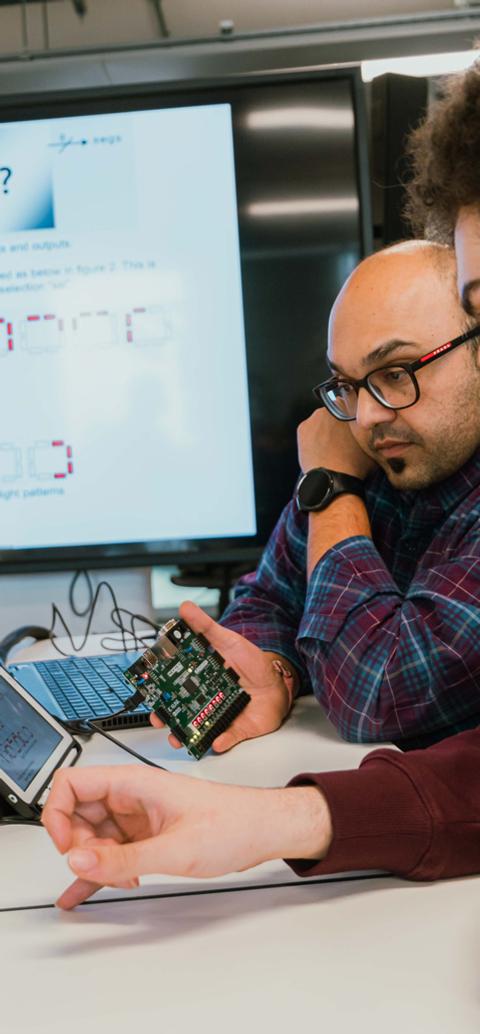 Students and a lecturer work with electronic hardware and software during an engineering class