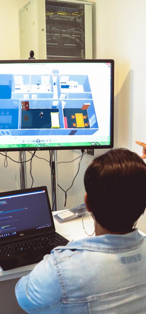 Information technology students discuss a digital simulation and source code in a university computer lab.