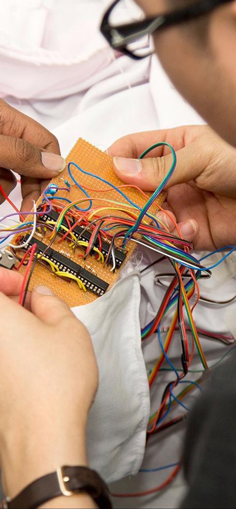 Two male students sitting at a desk, working on a piece of electronic equipment