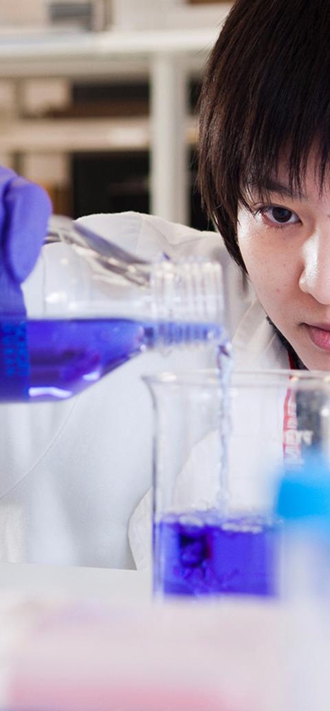 Female student in white lab coat prepares a liquid experiment in the lab at middlesex university