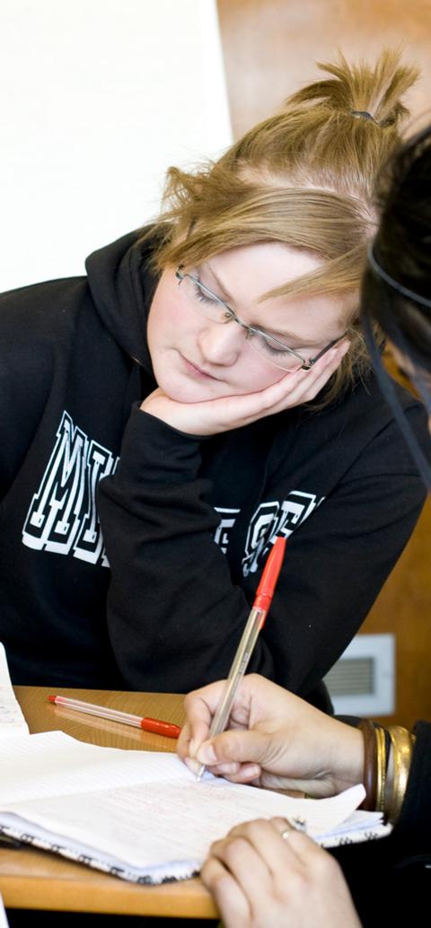 A student sitting on a red couch listening