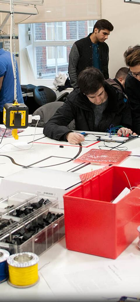 students work with circuit boards in busy laboratorys