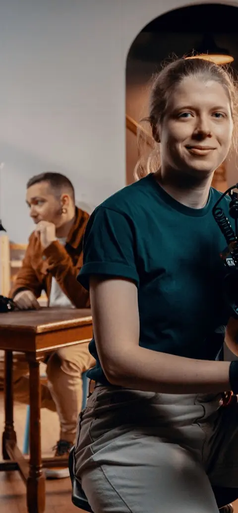 A student using a film camera with two people behind him on set