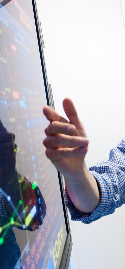 lecturer pointing to financial dashboard on large screen