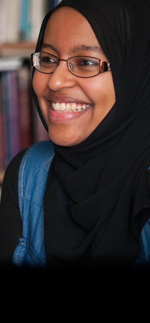 A Muslim female student smiling in a library