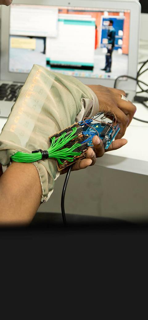 A student is sitting at a desk in front of a computer, working with electrical equipment