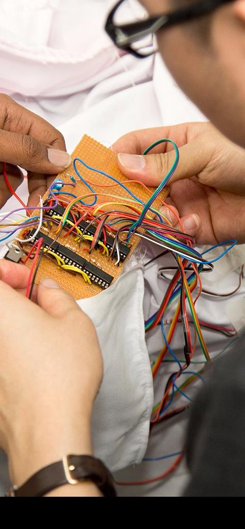 Two male students sitting at a desk, working on a piece of electronic equipment