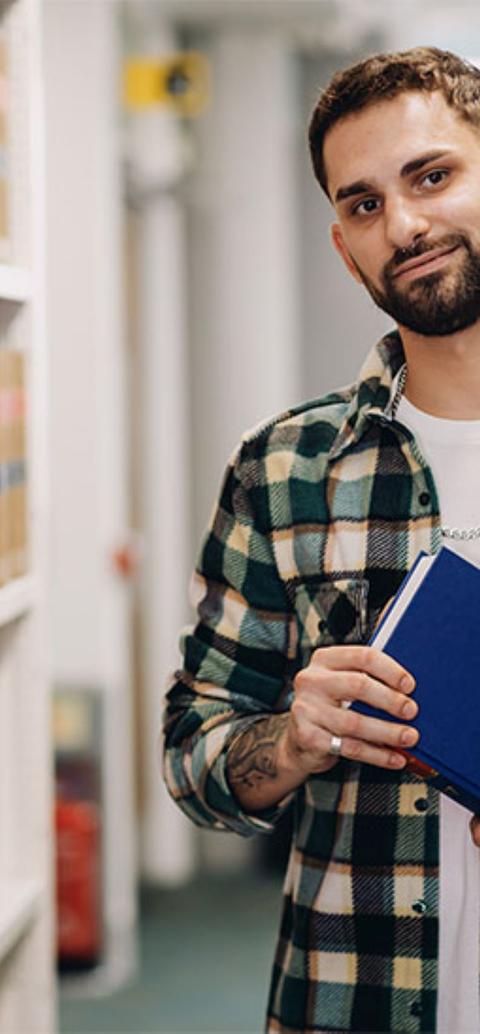 Male law student in the Sheppard Library standing between book shelves