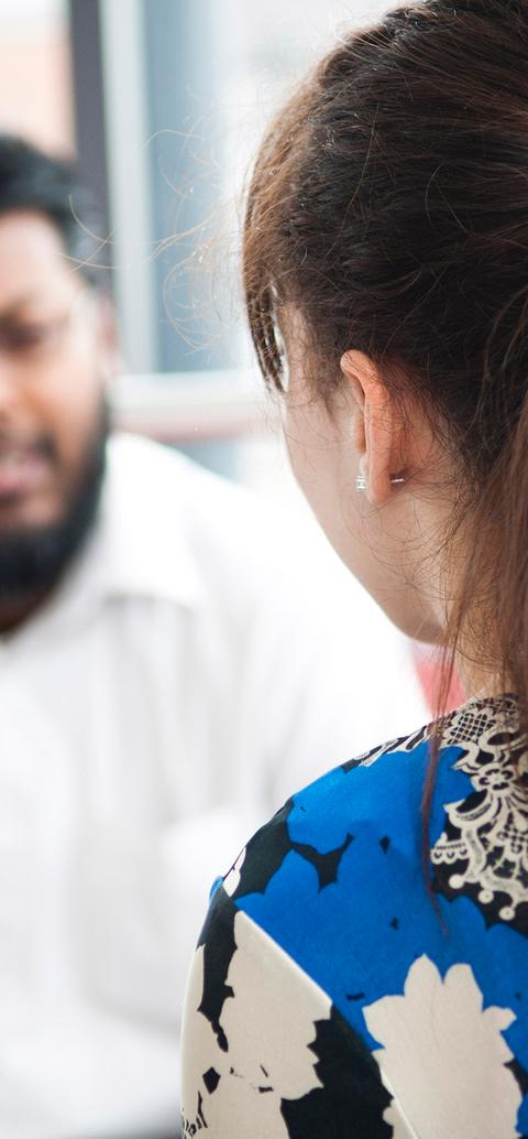 close up of back of patients head as they talk to therapist in background