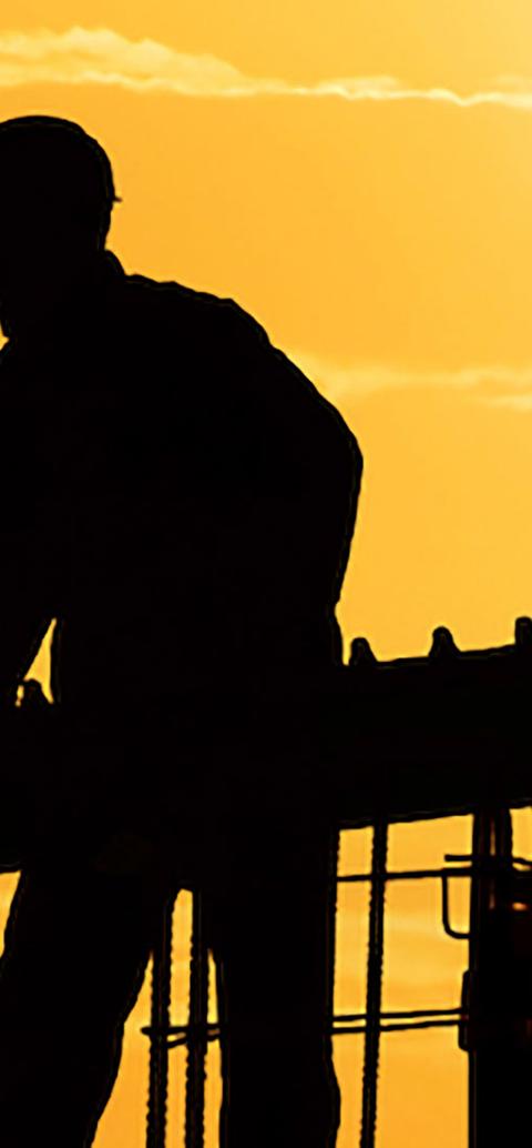 Dark silhouettes of two people working on a dockyard at sunset