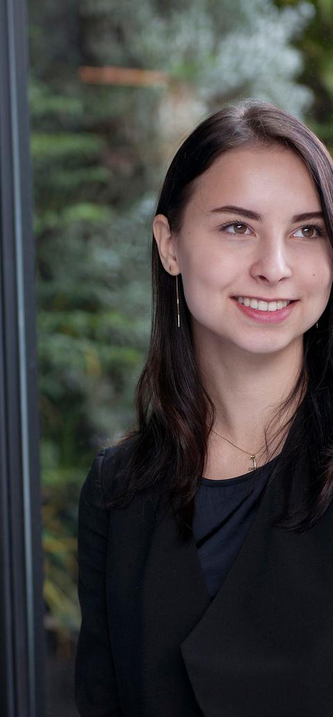 smartly dressed student, backdrop of large window looking out onto leafy background