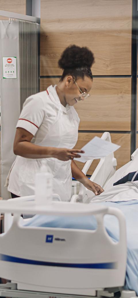 A nurse stands next to a dummy in a hospital bed