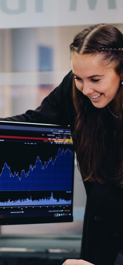 Students in a financial lab environment in a university setting looking at graphs on two screens
