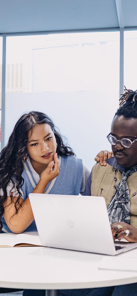 three students work together on laptop