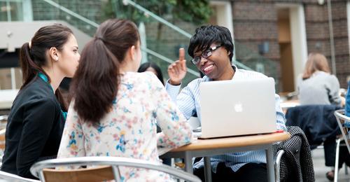 Three Middlesex University students sitting at a table in the quad