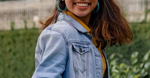 Person smiling in front of green plants
