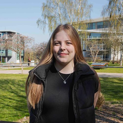 Abbi on campus on a sunny day with building in background