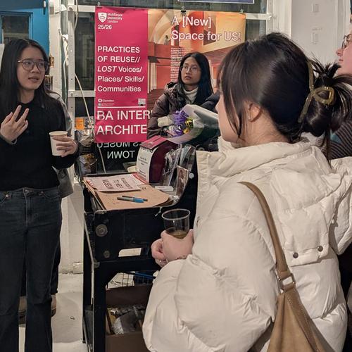 A young woman explaining a point tp three other young women at an exhibition