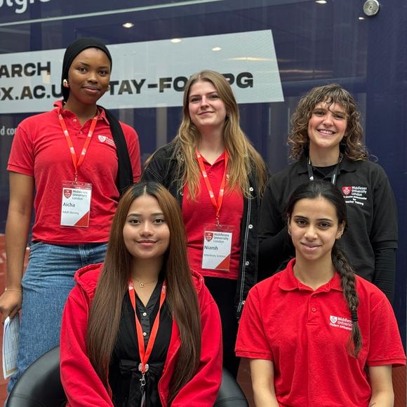 A group of five smiling people in branded open day tops