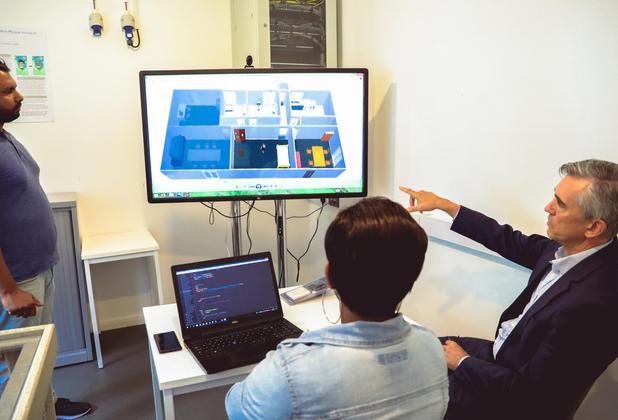 Information technology students discuss a digital simulation and source code in a university computer lab.