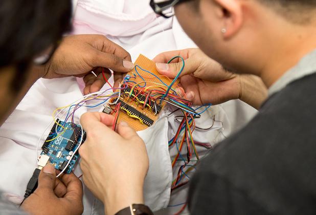 Two male students sitting at a desk, working on a piece of electronic equipment