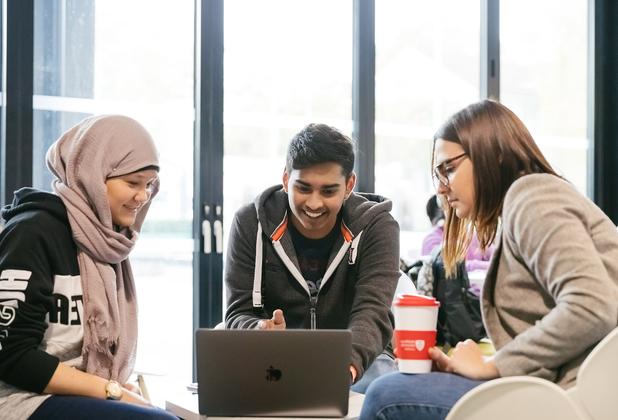 three students work informally at laptop
