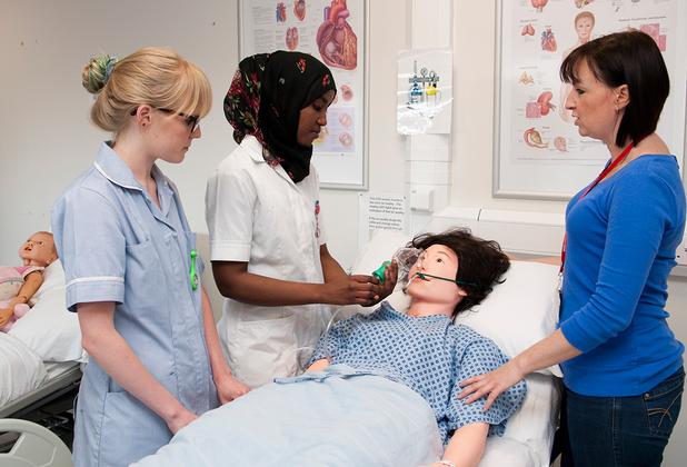 student nurses examining a dummy in class