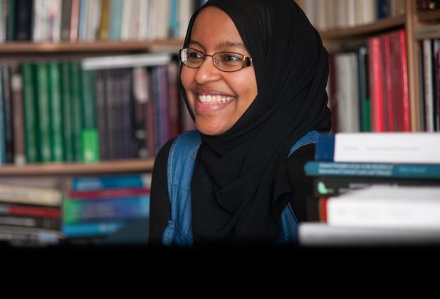 A Muslim female student smiling in a library