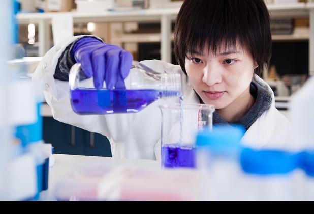 Female student in white lab coat prepares a liquid experiment in the lab at middlesex university