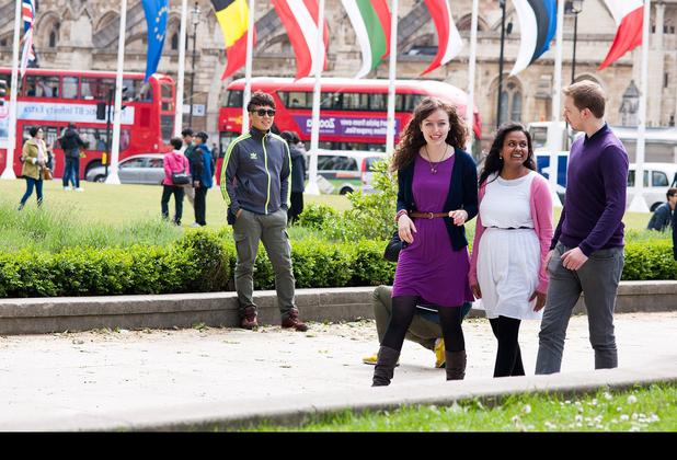 Three young people walking in a park, enjoying nature and each other's company. A perfect representation of international tourism and hospitality.