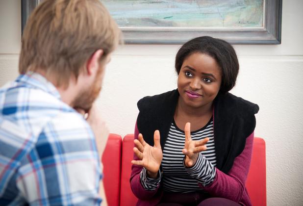 A young black female social work student interviews a client whose face is unseen